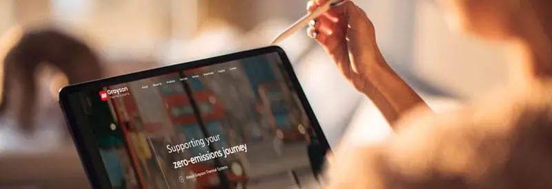 Woman holding an iPad with Grayson Thermal System's website homepage open