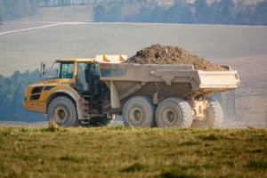 yellow Volvo A40E articulated dump truck earth mover fully laden with 25 tonne load driving across open countryside
