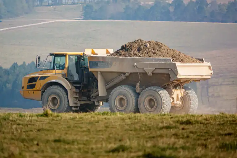 yellow Volvo A40E articulated dump truck earth mover fully laden with 25 tonne load driving across open countryside